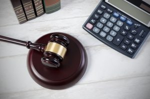 Imagem de calculadora ao lado de martelo da justiça representando os principais erros ao contratar um advogado correspondente