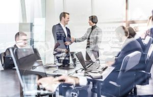 Imagem de mulher e homem brancos de pé apertando as mãos para ilustrar como melhorar o relacionamento entre funcionários de um escritório jurídico