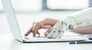 Mão de inteligência artificial e mão humana digitando no computador representando a inteligência artificial na advocacia